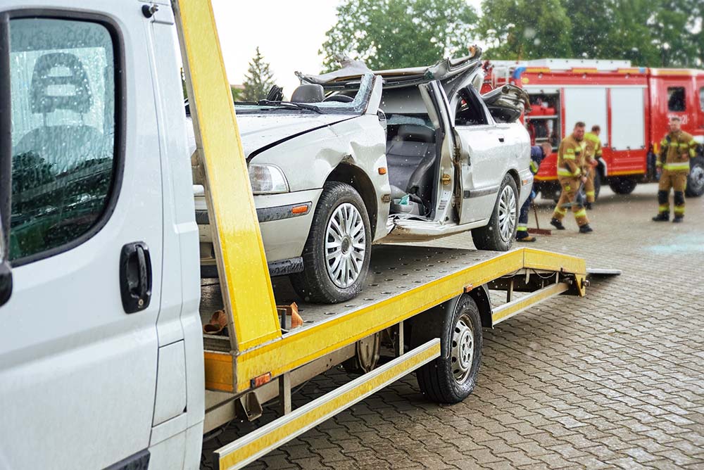 Wrecked car loading on tow truck after crash traffic accident, Concept of dangerous driving after drinking alcohol, Roadside assistance concept